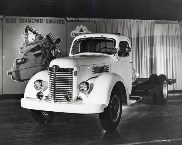 Three-quarter front view of an International KB-8 truck on display in front of a sign with information on the Blue Diamond engine.
