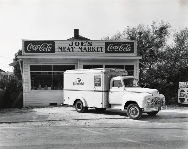 An International L-150 truck owned by the Fehr Baking Company parked in front of Joe's Meat Market. The side of the truck advertises "Fairmade; Fairmade is Good Bread." The original caption reads, "The new L-150 International operated by the Fehr Baking Company of San Antonio is shown in front of a neighborhood store which is one of dozens of similar daily shops. A feature of this truck's special bakery equipment is the 18 stainless steel shelves (9 on each side) which are movable and by a simple jerk, the bread and cake cartons can be made to travel to the rear and thus facilitate quick deliveries. Besides the rear doors there is a door on the right side which leads to a front compartment. L. Ghirst is president of the Fehr Baking Company."