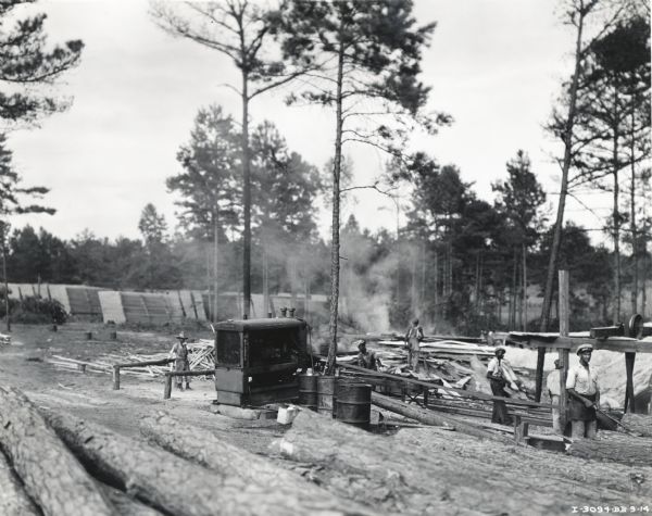 Men working outdoors at a sawmill powered by an International PD-80 Diesel power unit purchased by the A.B. Carroll Lumber Company.