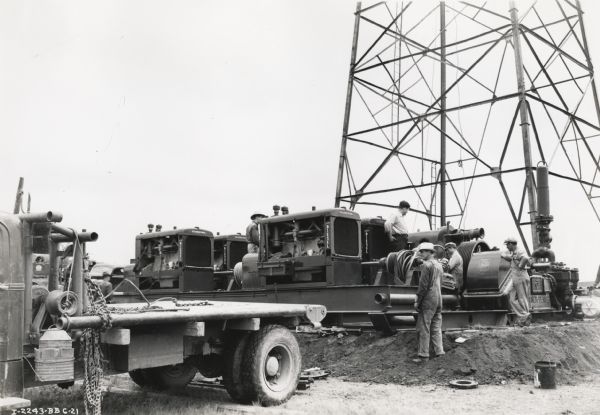Men gather around International PD-80 Diesel power units as they set them up on a drill rig.