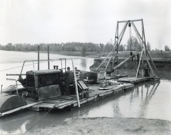 A man operates an International PD-80 power unit mounted on a suction dredge for sand and gravel. The power unit is owned by Roy Deringer of Ithaca, Michigan, and uses 35 gallons of oil in nine hours, producing 100 yards of sand and gravel per day.