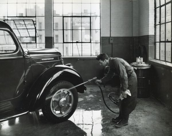 A man uses a hose to wash the tires of an International truck in the third floor wash rack at International Harvester's Manhattan truck branch.