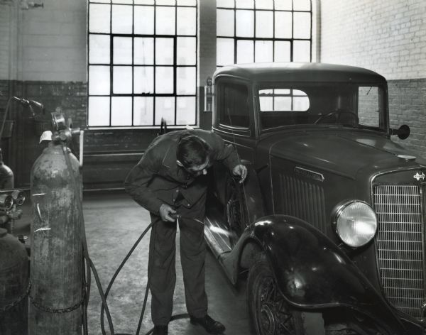 A mechanic stoops to weld a part of an International truck in the welding and paint room of International's Manhattan truck branch.