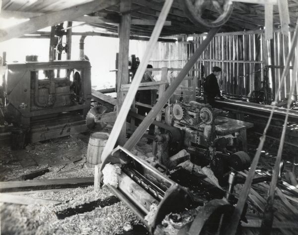 Men use machinery inside a sawmill powered by an International PA-40 power unit. The mill was owned and operated by Bert Rubeck & Son.