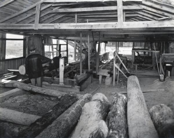 Men operating machinery in a sawmill powered by an International PK-40 power unit.