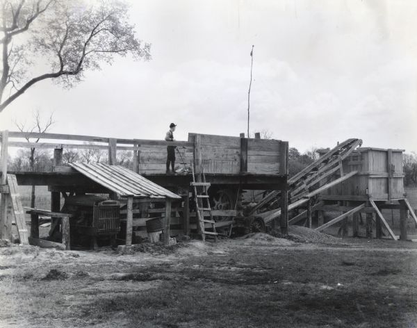 A young man stands on a platform above an International PA-80 power unit (converted into a P-100) at a gravel pit owned by Mogg County.