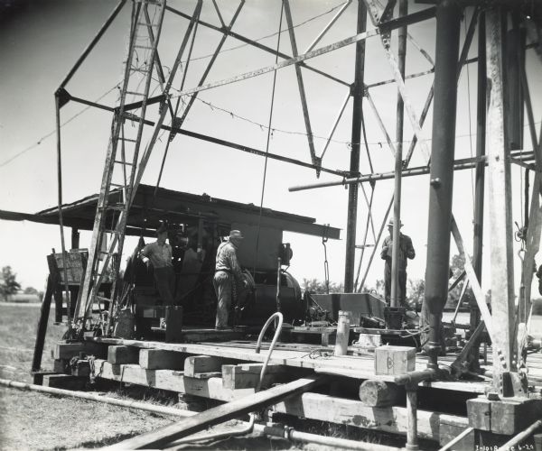 Three men stand on a platform near two butane-operated International PA-100 power units.
