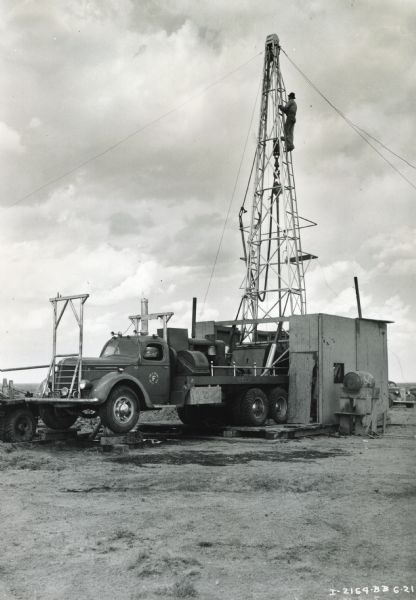 International D-346-F 3.5 to 7 ton truck equipped with a Failing Supply Co. Model 55 core-drilling and shallow-well-drilling rig. The truck was also equipped with an International PA-50 power unit. A man is climbing up the body of the drill rig.