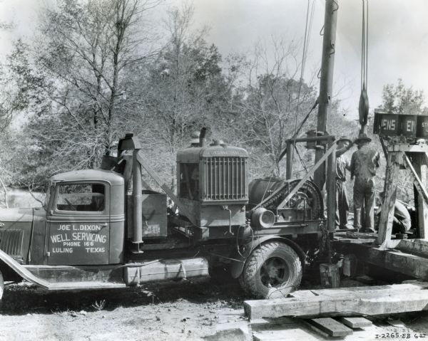 Men stand on a platform behind an International C-40 truck outfitted with an A-4 power unit and a Wilson winch. The truck and equipment were owned by Joe L. Dixon.