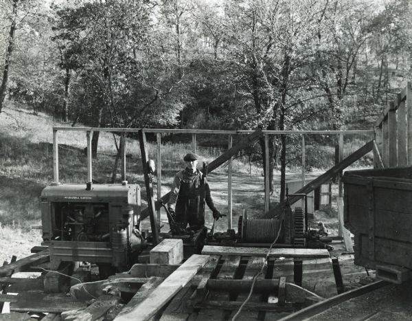 A man standing near an International U-7 power unit used to operate a drum hoist which pulls cars up a 500 foot slope from a mine.