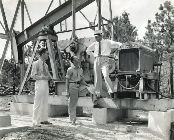 D.W. Norred (left), International Shreveport branch, Roy Foster, switchman of the Rajo Oil Corporation, and Jack Anderson of Jack Anderson Company, an International industrial dealer in Longview, Texas, stand near a Rajo Oil Corporation oil drill powered by an International power unit.