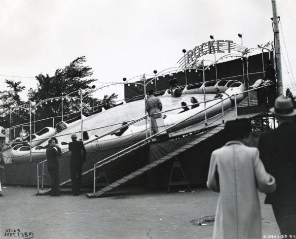 Men and women look on as people ride on the "Rocket" amusement ride at the Canadian National Exposition. The ride was owned by Miller Amusement Enterprises and powered by an International U-7 power unit.