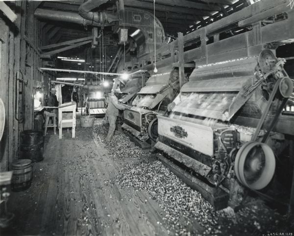 Men operate machinery powered by an International PD-80 power unit inside the Peacock cotton gin.