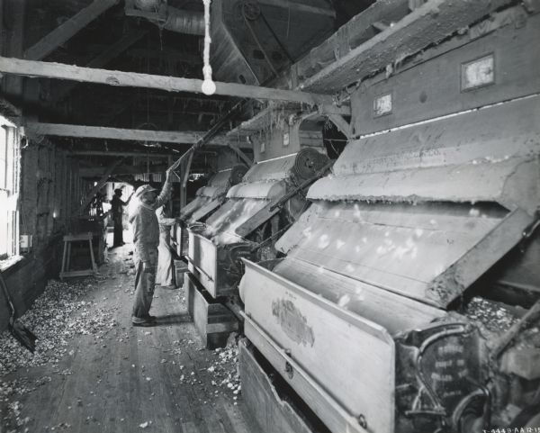 Three men operate machinery inside a cotton gin owned by O.L. Garmon.