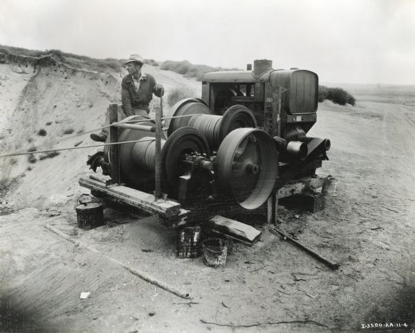 A man operates machinery powered by an International PA-50 power unit owned by Starbuck Construction Company.