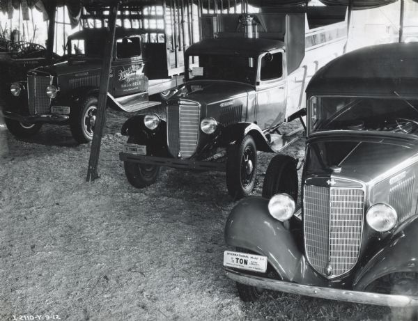 Three International trucks on display beneath a tent at the Wisconsin State Fair. The truck on the far left is painted with the text: "Miller Brewing Co. / 'High Life' Beer / Milwaukee." Each truck also has a sign identifying model and capacity (left to right): C-50, C-30, C-1.