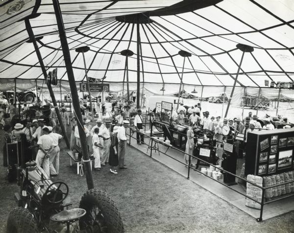 People gather around displays of International Harvester equipment set up beneath a tent at the Missouri State Fair.