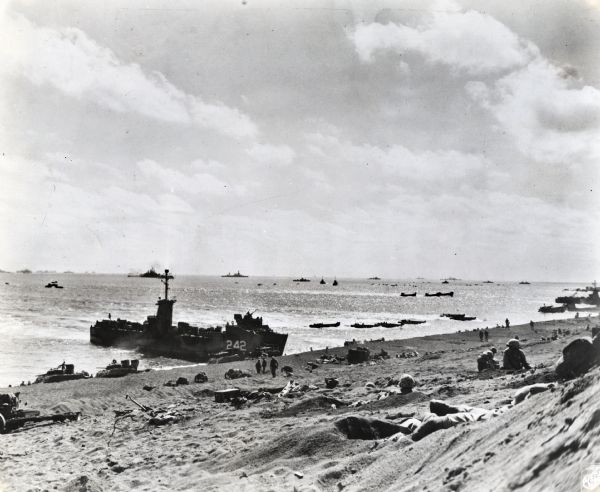 Marines on the beach and military boats, including an LSM 242, in the water at Iwo Jima.