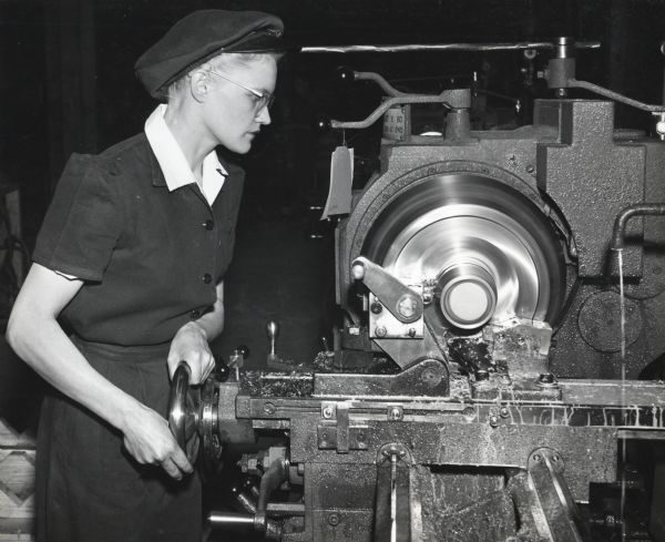 A female factory workers uses machinery to make artillery shells at International Harvester's New Brighton Works.