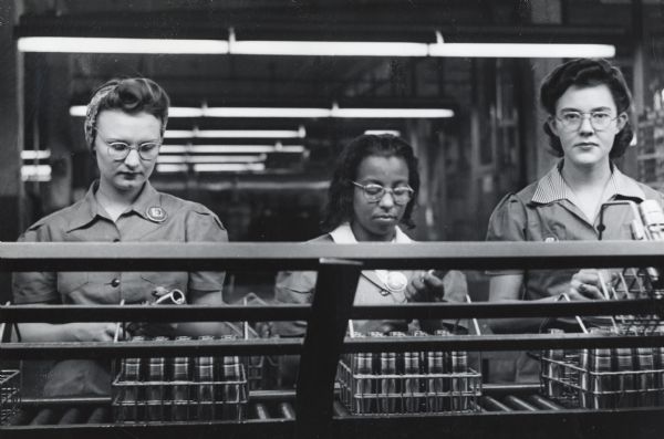 Three female factory workers inspect 40-millimeter artillery shells at International Harvester's West Pullman Works.