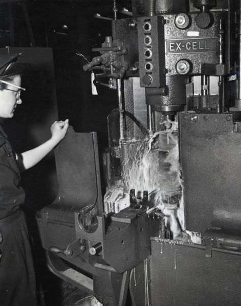 A female factory worker operates an automatic machine tool at International Harvester's New Brighton Works.