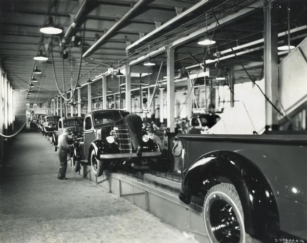 Factory workers and trucks on an assembly line at International Harvester's Springfield Works.