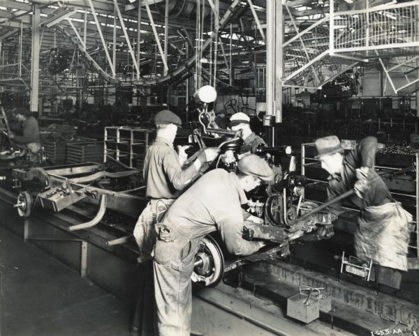 Factory workers and trucks on an assembly line at International Harvester's Springfield Works.