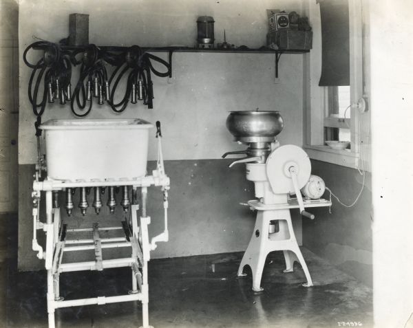 A milking machine and an electric enamel Primrose cream separator in a room on the farm of Mr. Jerry Bacon.