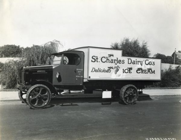 Side view of an International truck used by the St. Charles Dairy Company. The side panel features the text: "Delicious Ice Cream" along with an illustration of a woman skiing.