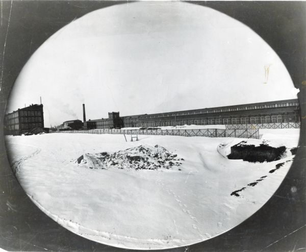 Vignetted view of a factory building in a snow-covered landscape.