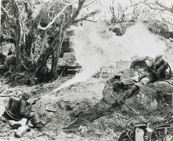 Elevated view of marines Private Richard Klatt, of North Fond du Lac, Wisconsin (left), and Private First Class Wilfred Voegeli, as they set fire to brush to clear the way to Mount Suribachi on Iwo Jima.