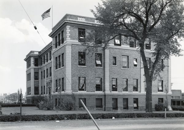 Exterior view of the southeast side of the General Office building of International Harvester's Quad-Cities Tank Arsenal. The building has an American flag flying from its roof.