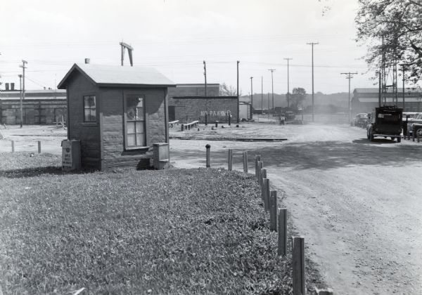 View of the grounds of International Harvester's Quad-Cities Tank Arsenal, looking south towards the proposed East boundary fence line. A man is standing in a small building on the left, perhaps a guardhouse.
