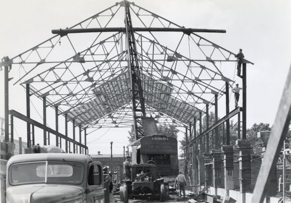 Men use a crane to work on the "Micro-Westco Addition" at International Harvester's Quad-Cities Tank Arsenal. The text on the crane reads: "Universal; Excavating, Back Filling, Car Unloading, Steel Erecting, Pile Driving."