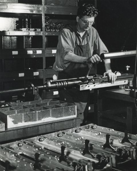 Factory worker William Nolan works on the final assembly of a 20 mm cannon before proof firing at International Harvester's St. Paul Works.