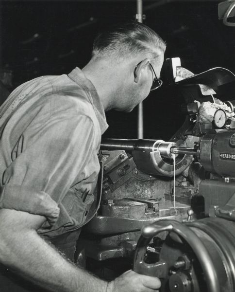 Factory worker Emil Borchert grinds the shell receiver end of the barrel of a 20 mm cannon at International Harvester's St. Paul Works.