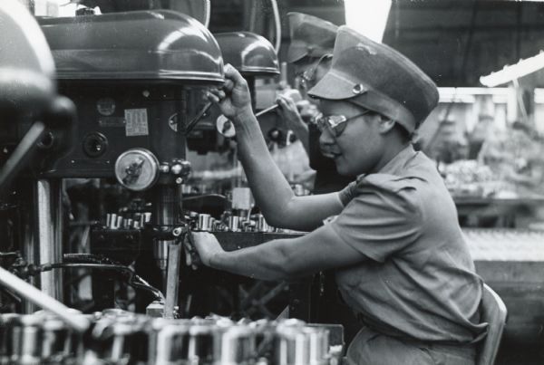 Close-up of factory worker Dorothy Ozen wearing safety glasses while operating a drill press used in war production at International Harvester's West Pullman Works.