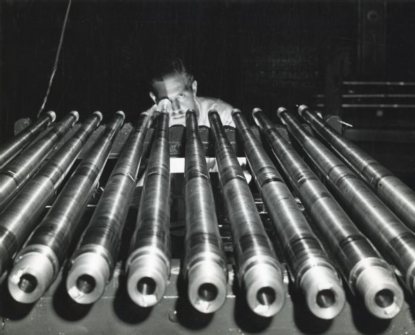 Factory worker Oscar Olsen uses a borescope to inspect 20mm cannons at International Harvester's St. Paul Works.