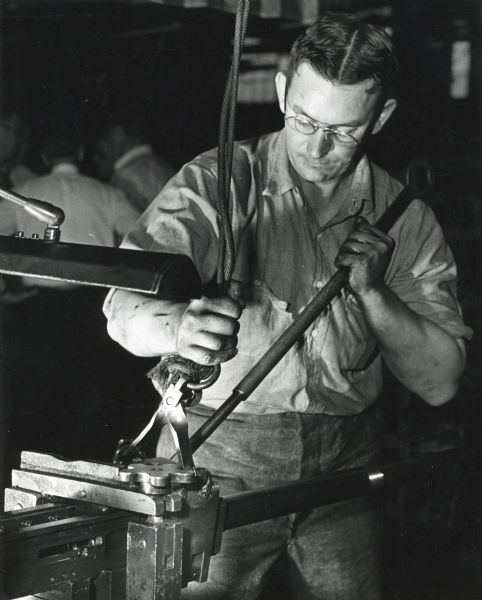 Factory worker James Matzke clamps the barrel of a 20mm cannon at International Harvester's St. Paul Works.
