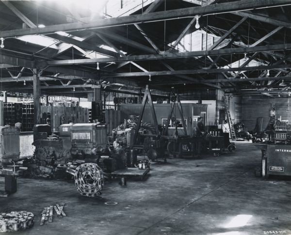 Two men working in the service shop of the Brown Tractor Company, an International Harvester dealership. Several tractors are in the shop.