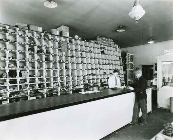 Two men stand at a parts counter in an International Harvester farm equipment dealership.
