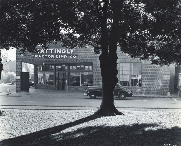 Exterior view through trees of a store operated by Mattingly Tractor & Implement Company, an International Harvester dealership.