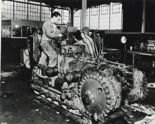 J.D. Adams and a mechanic work on an International crawler tractor (TracTracTor) in the service shop of J.D. Adams Co., an International Harvester dealership.