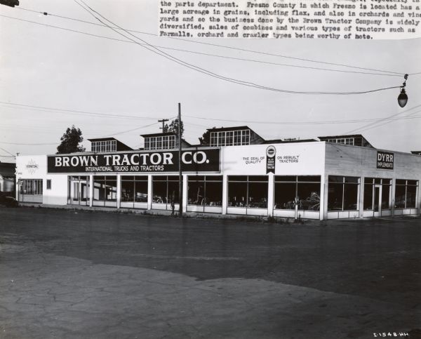 Exterior view of the Brown Tractor Co., and International Harvester dealership. A sign on the outside of the building advertises: "International Trucks and Tractors" and "Dyrr Implements."