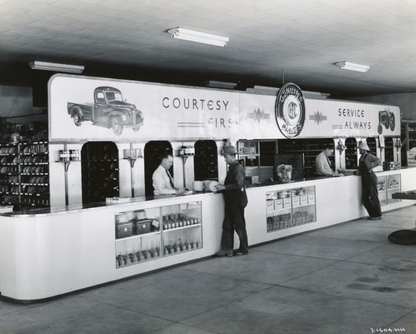 Customers at the parts counter of an International Harvester dealership owned by the Chisholm Brothers of Snake River Valley, Idaho. Behind the counter (left to right) are John F. Chisholm and Donald A. Chisholm.