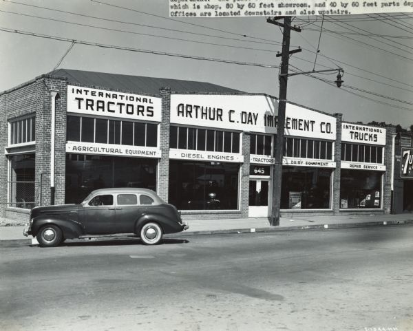 View from street of a car parked in front of the Arthur C. Day Implement Co. storefront. The Arthur C. Day Implement Co. was an International Harvester dealership, and was operated by Arthur C. Day and E.L. Johnson.