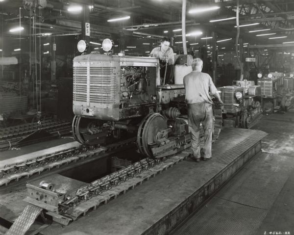 Factory workers on a crawler tractor (TracTracTor) assembly line at International Harvester's Tractor Works.