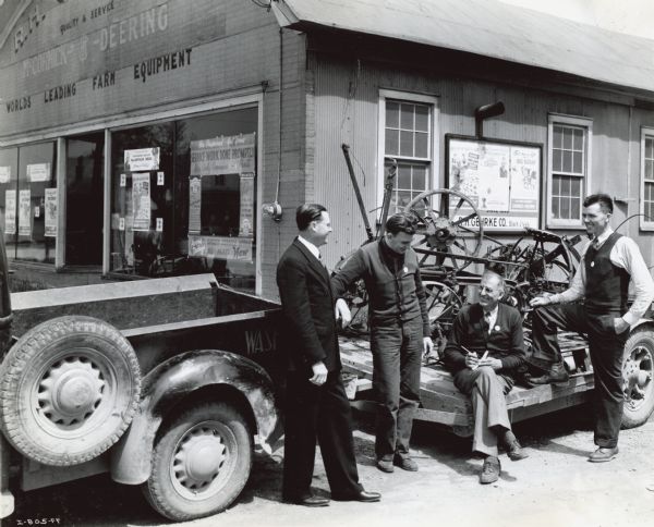 Four men outside R.H. Gehrke Company, an International Harvester dealership. The men are, (left to right): H.P. Patheal, assistant manager of the Green Bay branch, Howard Gehrke, R.H. Gehrke (seated) and Scoutmaster Edward G. Shaw. The men helped organize the local "MacArthur Week" scrap drive.