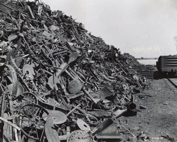 A large pile of scrap metal near a railroad track.