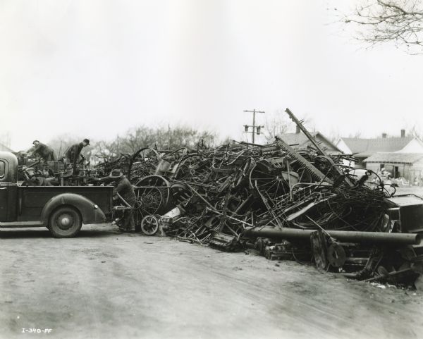 Farmers unload scrap metal onto a large pile as part of a wartime scrap drive. 

